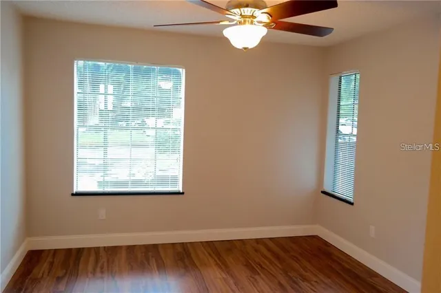 a view of an empty room with wooden floor and a window