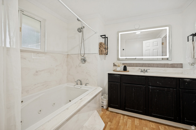 1215 8th Street Ogden, UT 84404 - Photo 21 of 39 Bathroom featuring a jetted tub with marble-look surround, a black vanity with marble-look countertop, a back-lit vanity mirror, and wood-finish flooring