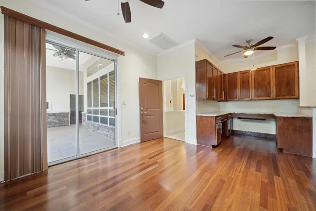 a view of a kitchen with furniture a ceiling fan and wooden floor