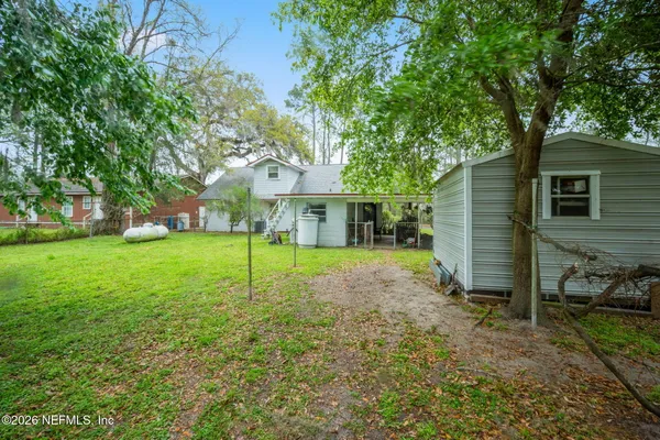 a view of a house with backyard and a tree