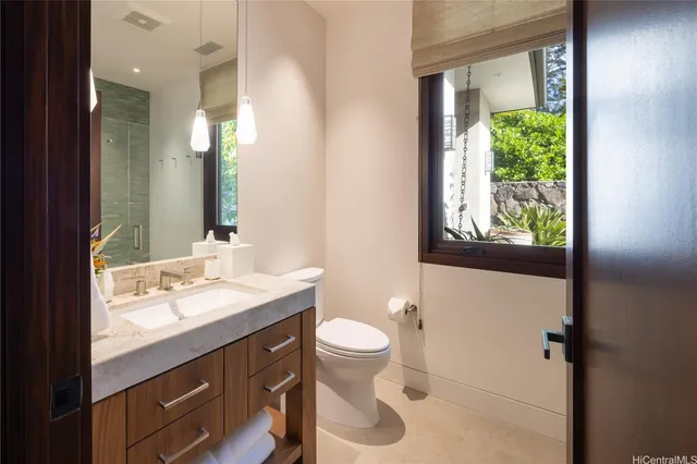 a bathroom with a granite countertop sink a toilet a mirror and a window