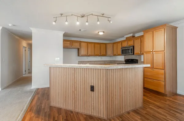 a kitchen with kitchen island granite countertop wooden cabinets a stove a sink and a refrigerator