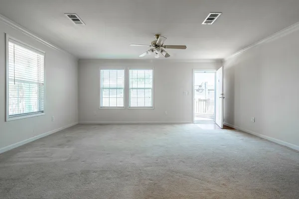 an empty room with chandelier fan and windows