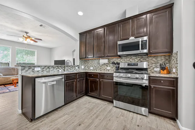a kitchen with stainless steel appliances wooden floors wooden cabinets dining table and chair