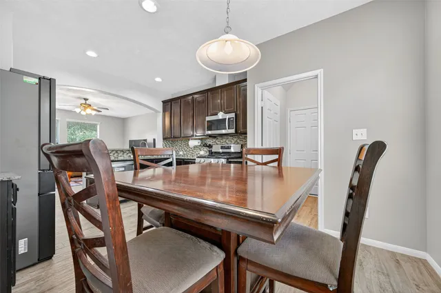 a kitchen with stainless steel appliances granite countertop a refrigerator a stove a dining table and chairs with wooden floor