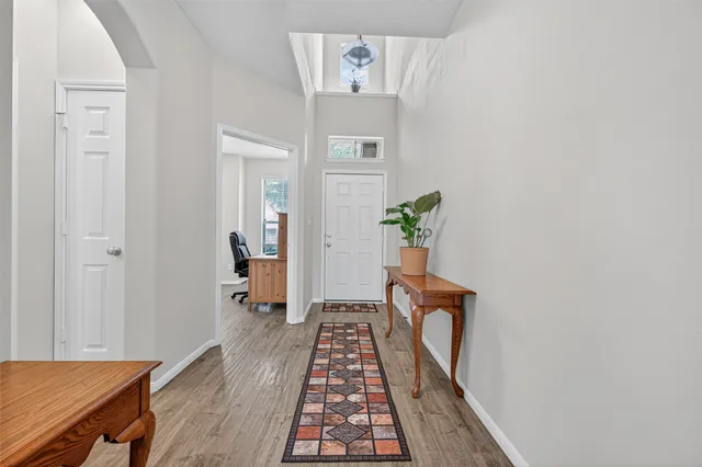 a view of a hallway with wooden floor and a dining room