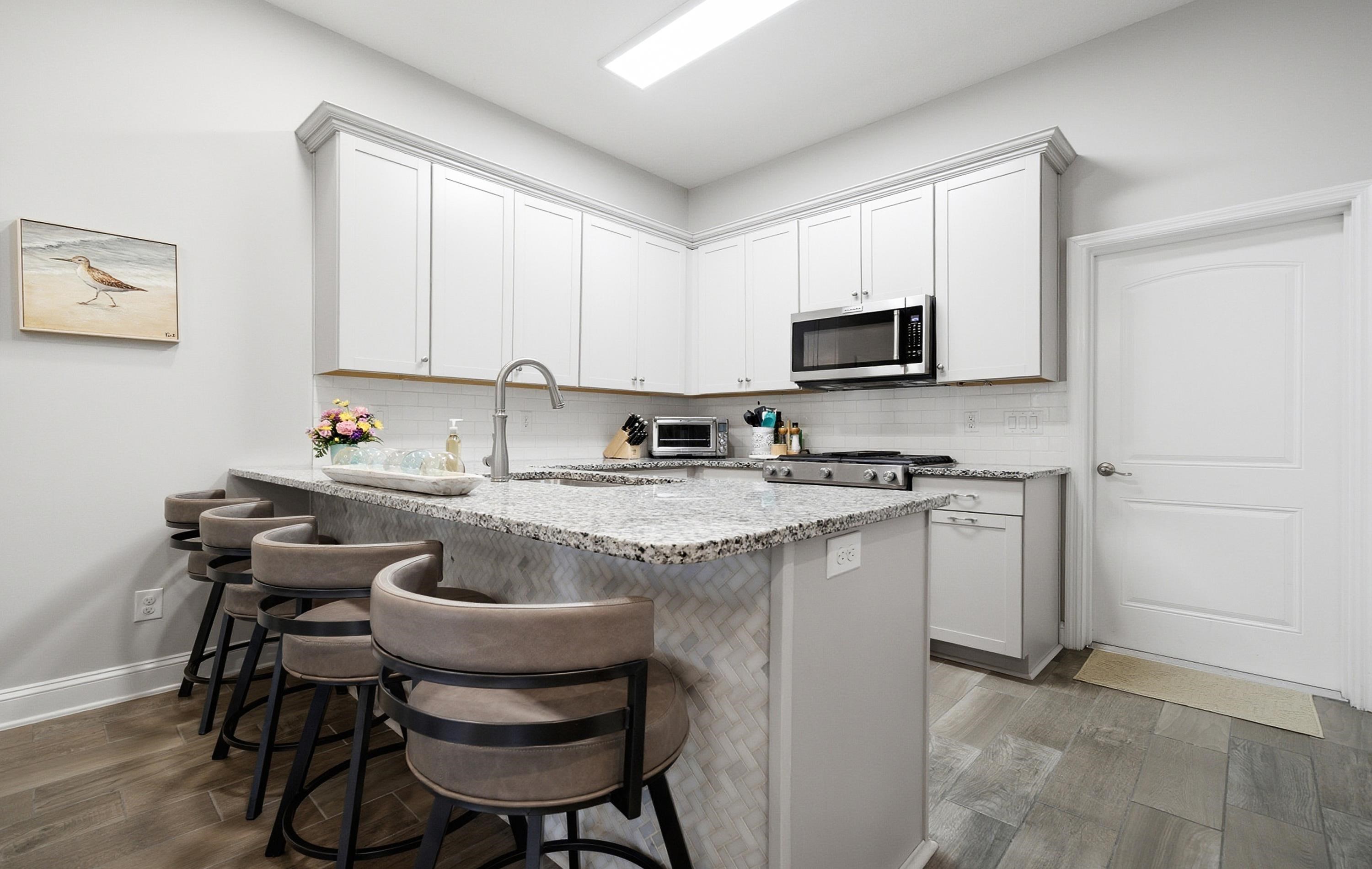 200 Grand Ravine Drive St. Augustine, FL 32086 - Photo 8 of 34 Kitchen featuring light stone counters, dark wood-style floors, a breakfast bar area, and white cabinets