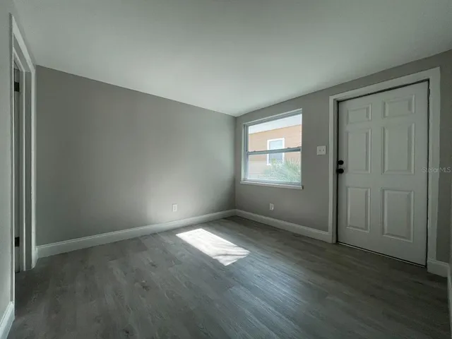 an empty room with wooden floor and windows