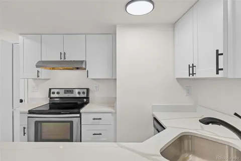 a kitchen with stainless steel appliances a stove a sink and white cabinets