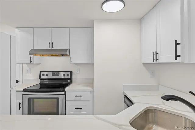 a kitchen with stainless steel appliances a stove a sink and white cabinets