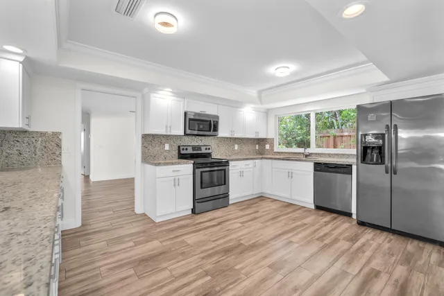 a kitchen with a refrigerator a sink a stove a microwave and wooden floor