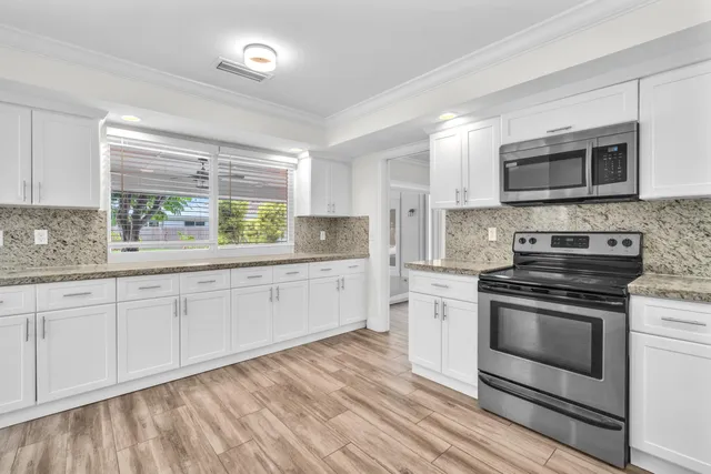 a kitchen with stainless steel appliances granite countertop a stove a sink and a microwave