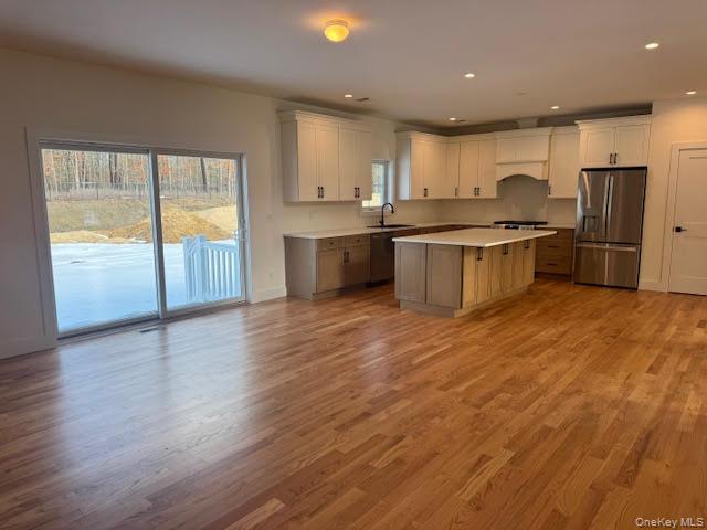 Lot #9 Colonels Path Manorville, NY 11949 - Photo 6 of 26 Kitchen featuring two tone cabinets, light countertops, stainless steel appliances, wood- floors, and a kitchen island