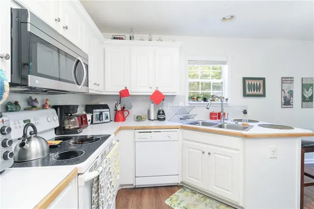 a kitchen with a sink dishwasher stove and white cabinets