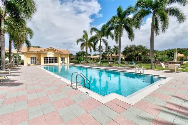 a view of swimming pool with a lawn chairs and palm trees