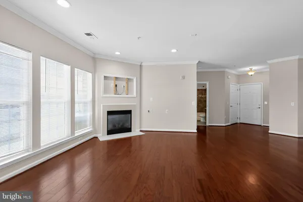 an empty room with wooden floor fireplace and windows