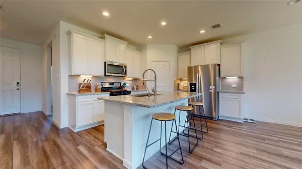 a kitchen with stainless steel appliances granite countertop a refrigerator and a stove top oven