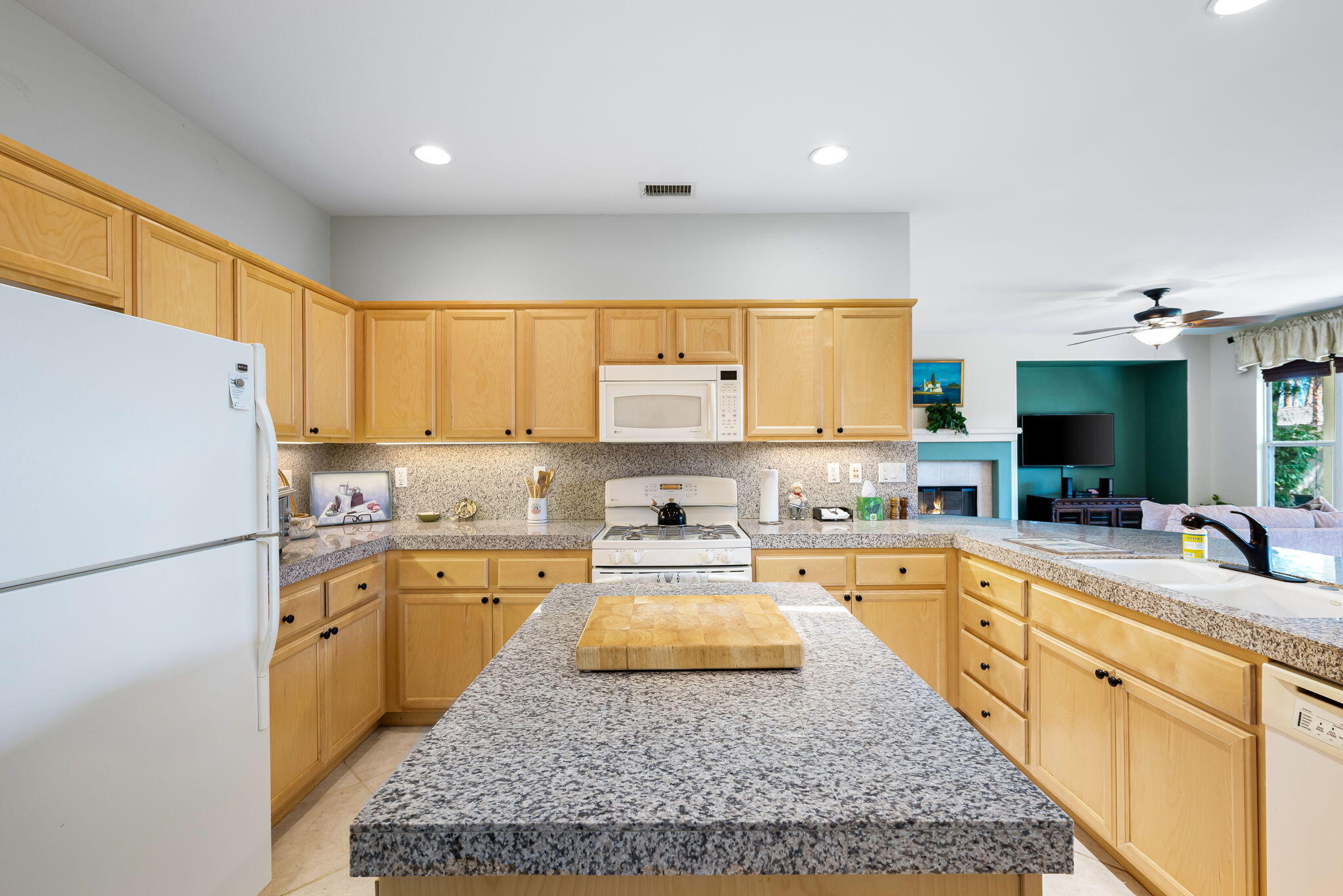 60246 Sweetshade Lane La Quinta, CA 92253 - Photo 21 of 76 a large kitchen with kitchen island a sink a stove a refrigerator and white cabinets