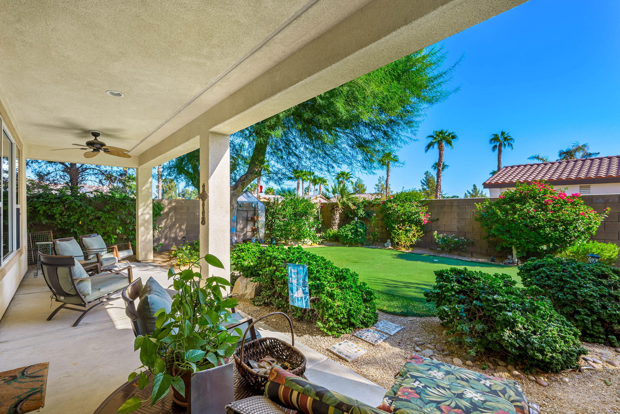 60246 Sweetshade Lane La Quinta, CA 92253 - Photo 34 of 76 a view of a patio with table and chairs potted plants and floor to ceiling window