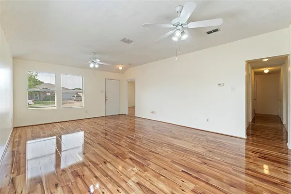 an empty room with wooden floor and windows