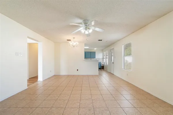 an empty room with kitchen view and natural light