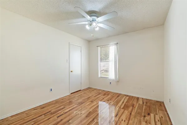 an empty room with a window and wooden floor