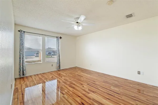 a view of a room with wooden floor and a ceiling fan