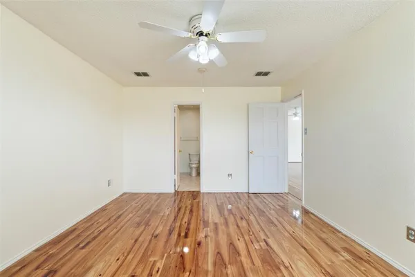 an empty room with windows and ceiling fan
