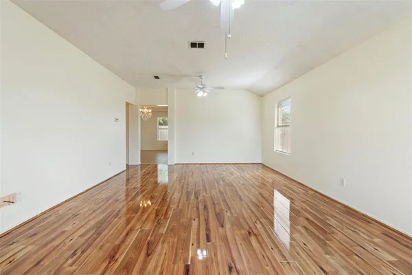 an empty room with wooden floor and ceiling fan
