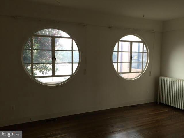 9904 Colesville Road Silver Spring, MD 20901 - Photo 8 of 23 an empty room with wooden floor windows and fireplace
