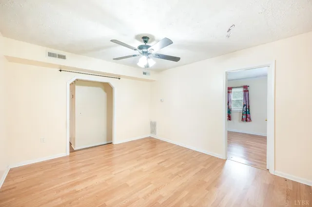 an empty room with a window and a fan