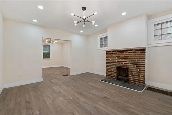 an empty room with wooden floor fireplace and windows
