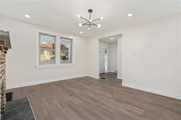 an empty room with wooden floor chandelier and windows