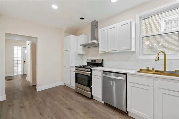 a kitchen with cabinets appliances and wooden floor