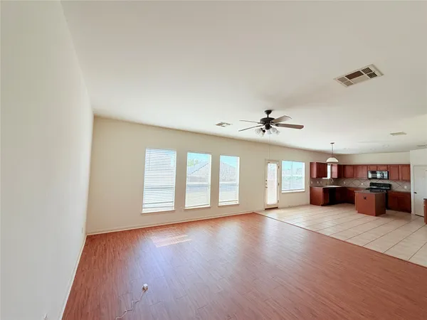 an empty room with wooden floor and windows