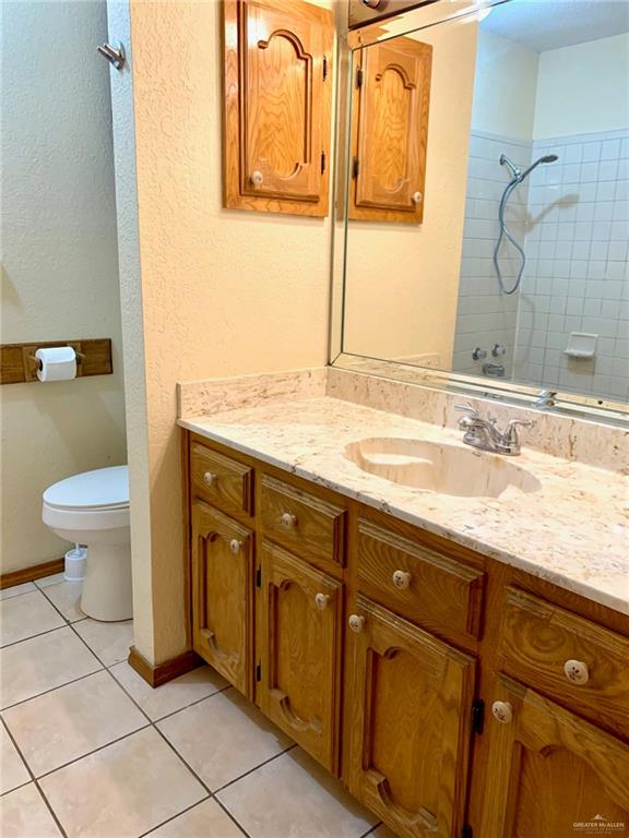 1311 East Pine Avenue Pharr, TX 78577 - Photo 13 of 14 a bathroom with a granite countertop sink a toilet and a mirror