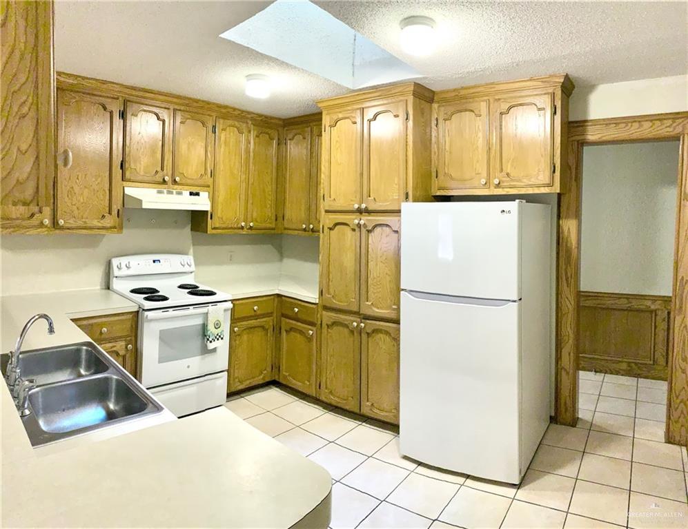 1311 East Pine Avenue Pharr, TX 78577 - Photo 2 of 14 a kitchen with a refrigerator sink and cabinets