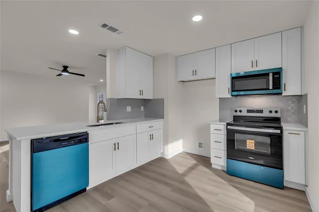 a kitchen with stainless steel appliances white cabinets a stove a sink and a microwave