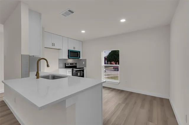 a kitchen with stainless steel appliances a sink a stove top oven a counter space and cabinets