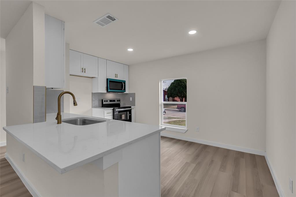 913 Roaming Rd Drive Allen, TX 75002 - Photo 7 of 21 a kitchen with stainless steel appliances a sink a stove top oven a counter space and cabinets