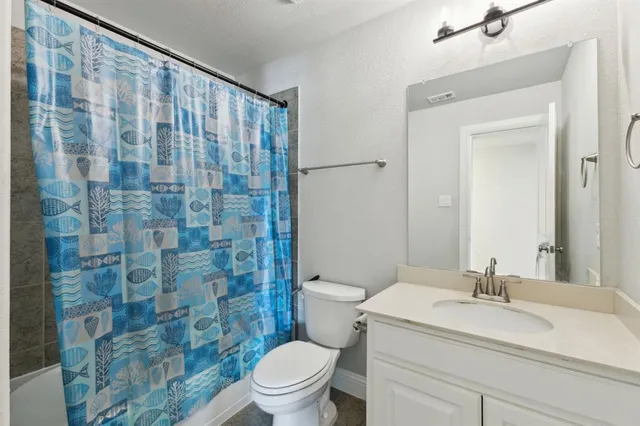 a bathroom with a sink a toilet and shower curtain