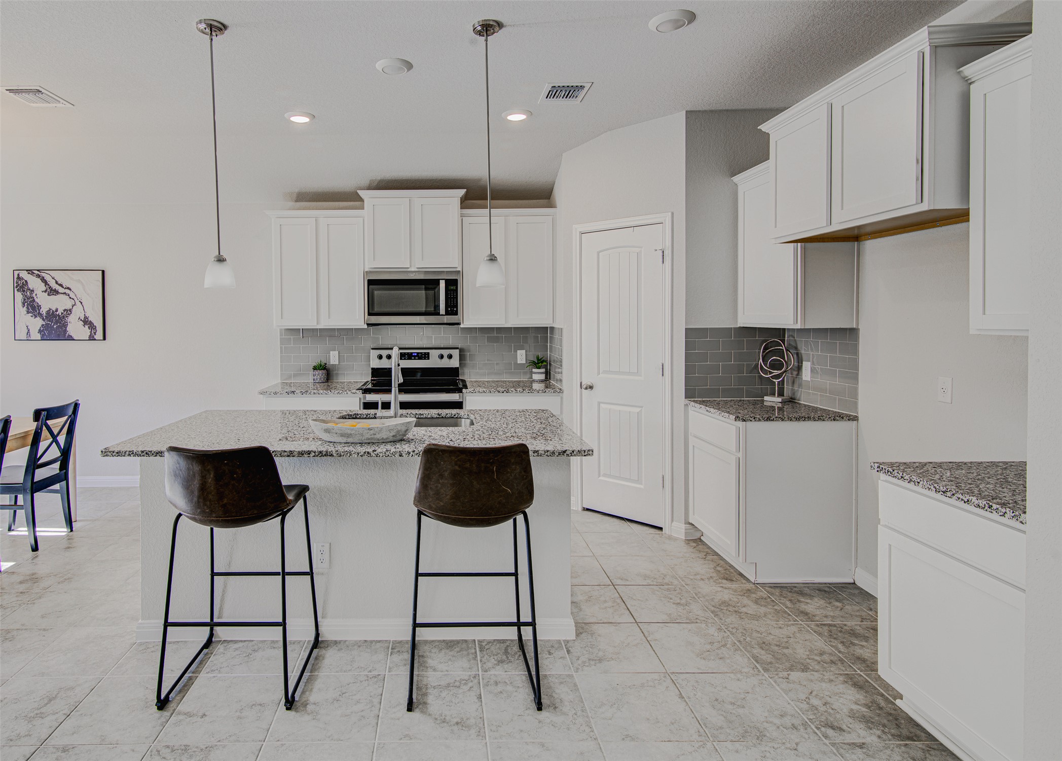 316 Pepper Mill Loop Burnet, TX 78611 - Photo 9 of 27 A well-lit kitchen with sleek white cabinetry and granite countertops offers a comfortable dining island.