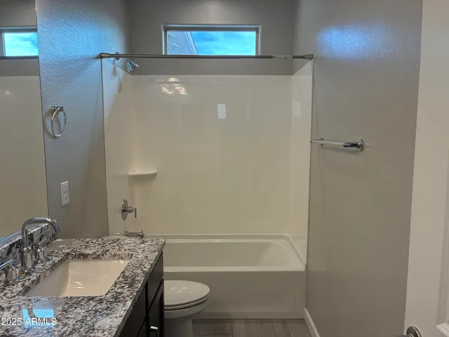 a bathroom with a granite countertop sink toilet and shower