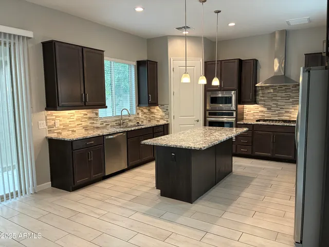 a kitchen with stainless steel appliances granite countertop a stove a sink dishwasher a refrigerator and a oven