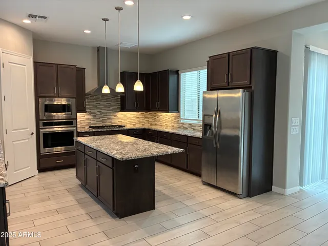 a kitchen with stainless steel appliances granite countertop a stove a refrigerator and a sink