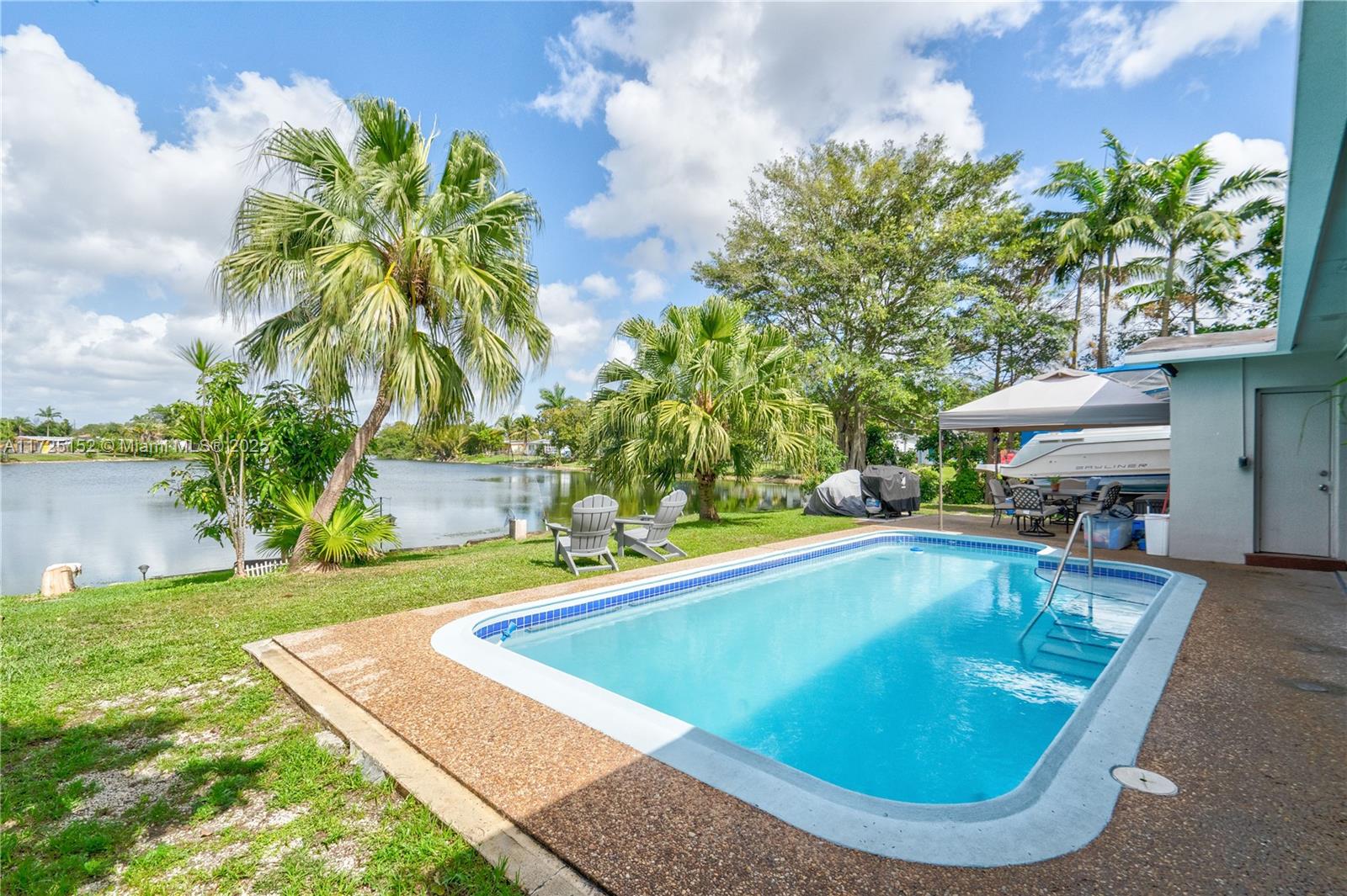 7271 Sunset Strip Sunrise, FL 33313 - Photo 42 of 45 a view of a swimming pool with lawn chairs under an umbrella