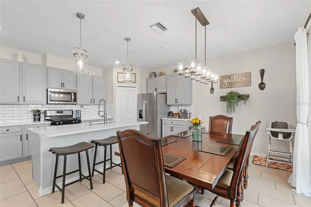 a dining room filled chandelier and kitchen view
