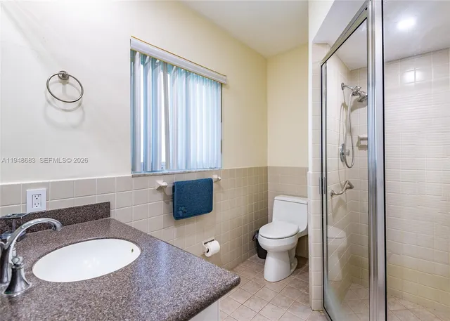 a bathroom with a granite countertop sink toilet mirror vanity and shower