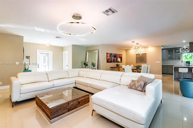 a living room with furniture kitchen view and a chandelier