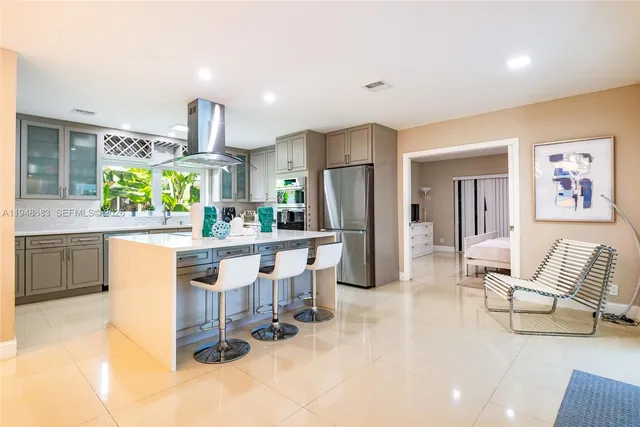 a kitchen with stainless steel appliances kitchen island granite countertop a refrigerator and a sink